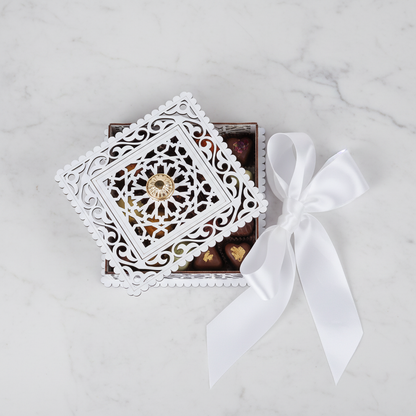 Cofre Sunduk como bombonera de boda rellena de chocolates artesanos con lazo de satén blanco sobre mármol